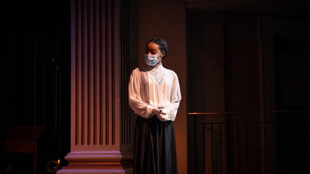 A woman with a medical mask on in 1910's era clothing