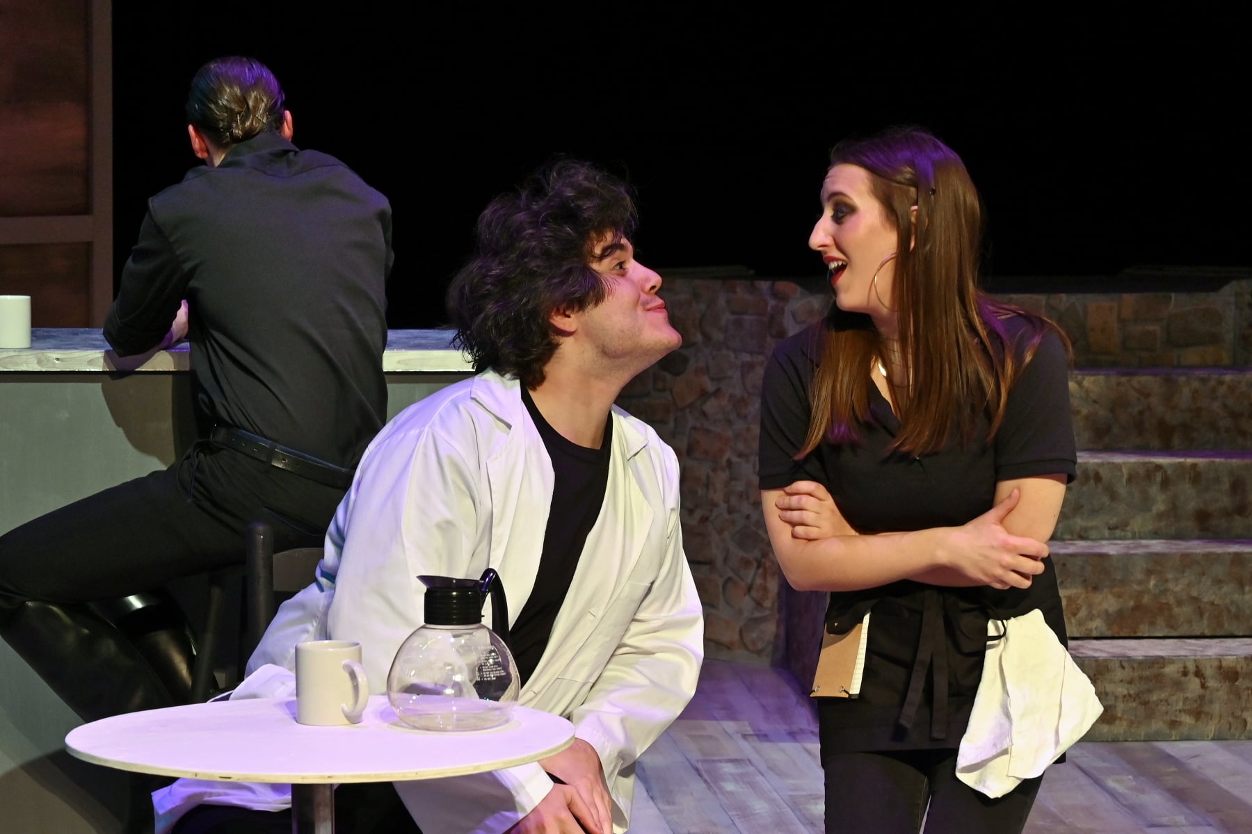 A man, sitting at a table and staring at a woman next to hime